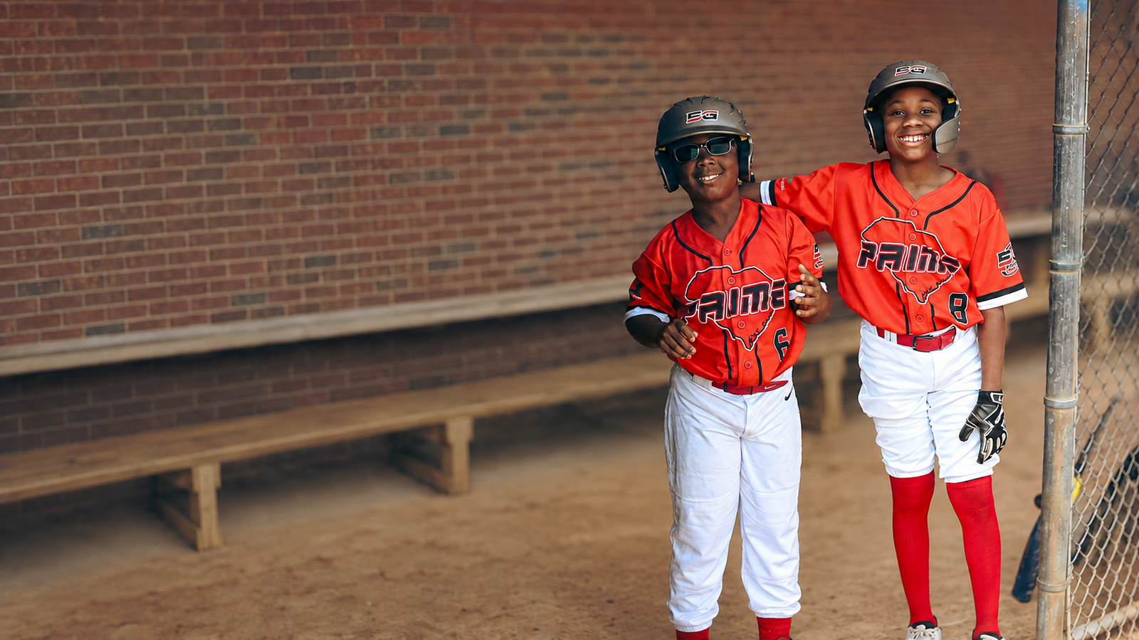 Two young 5G Prime players standing together in the dugout
