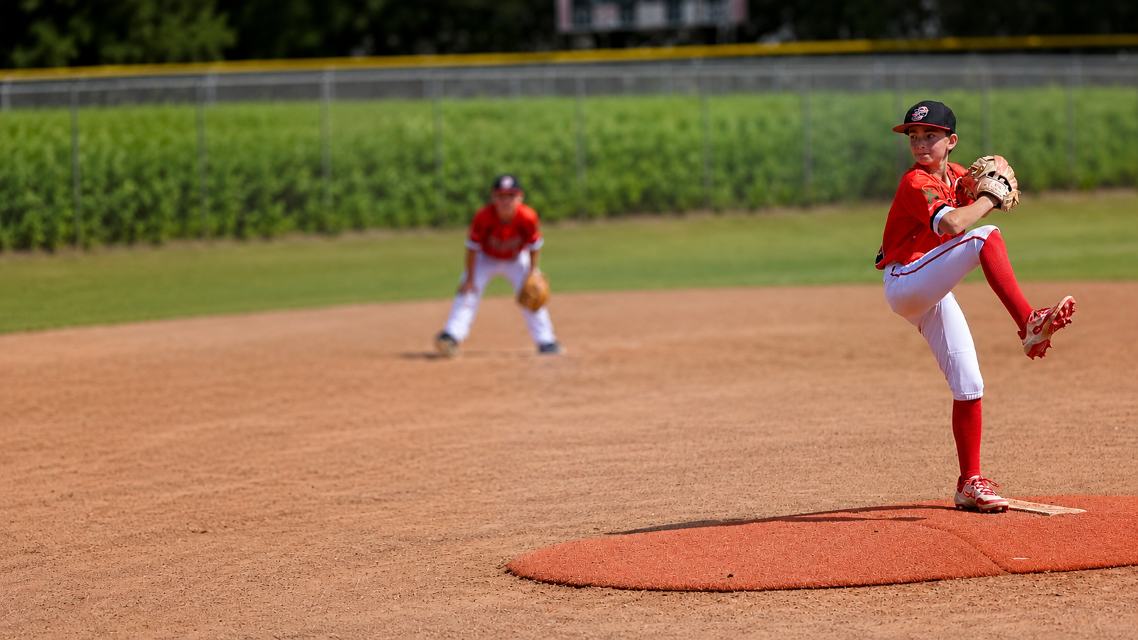 5G Prime baseball pitcher in red uniform mid windup
